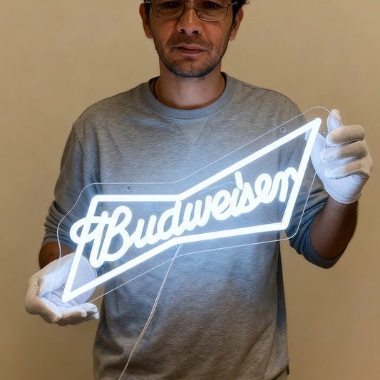 Man holding a neon Budweiser sign against a beige background