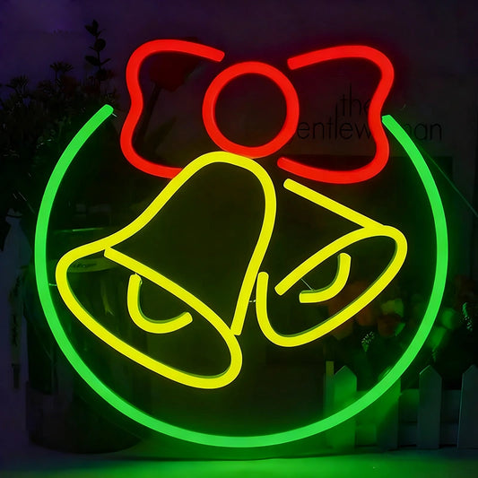 A neon sign featuring a red bow, lemon yellow bell, and green circular outline on a dark background.