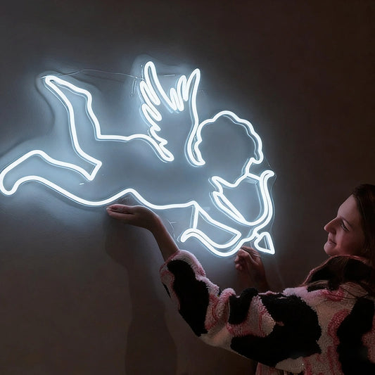 Woman holding a neon white light sculpture of a cupid figure on a dark background