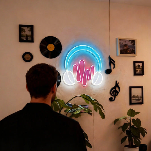 A person viewed from behind stands in front of a wall-mounted neon sign shaped like headphones with hot pink sound waves, surrounded by vinyl records, framed pictures, and plants in an indoor room.