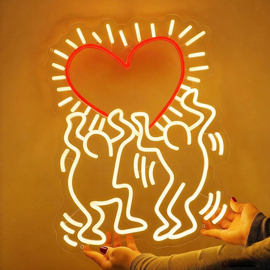 Neon light shaped like a heart with two people embracing, held against a textured wall.