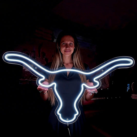 Person holding a neon sign shaped like a longhorn bull in a dark setting
