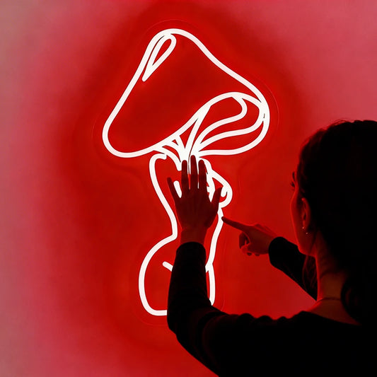 Person looking at a red neon sign of a mushroom head with lady's body on a dark background