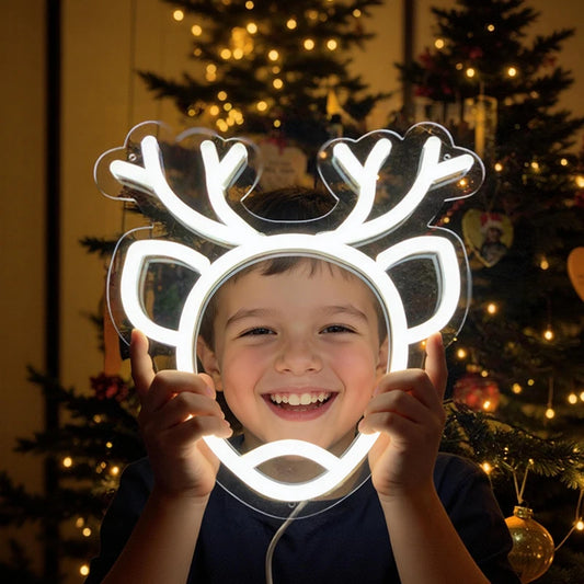 Child holding a neon reindeer sign in front of a decorated Christmas tree.