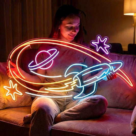 Person sitting on a couch with neon lights shaped like a rocket and planets.