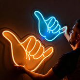 Two neon signs shaped like hands, one orange and one blue, on a dark background.