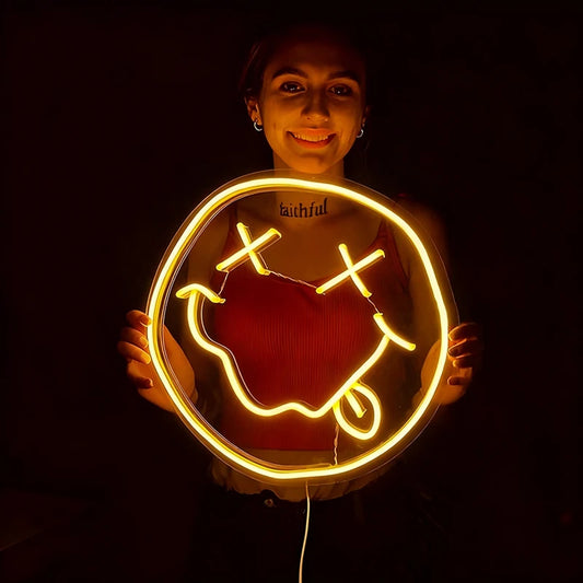 Person holding a lemon yellow smiley face neon sign on a dark background