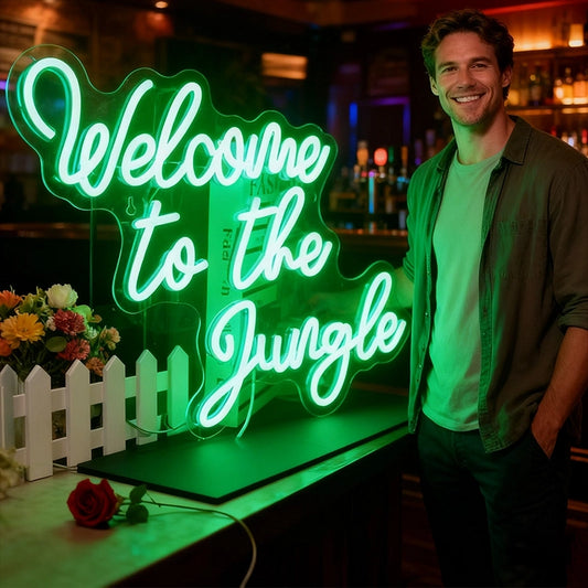 Man standing next to a neon sign that reads 'Welcome to the Jungle' in a bar setting.