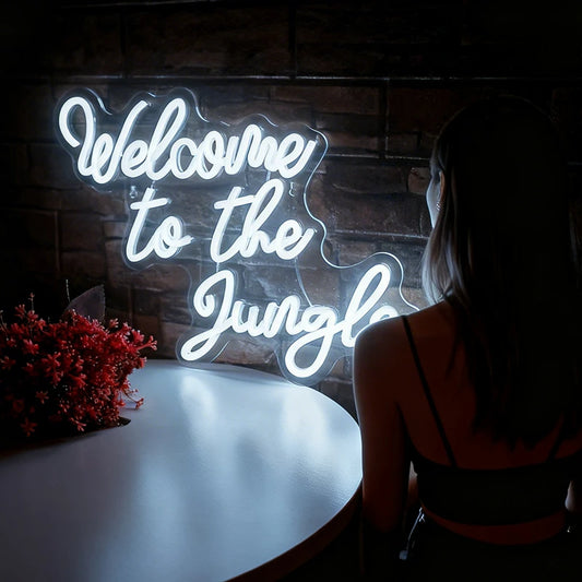 White neon sign reading 'Welcome to the Jungle' with a woman standing in front of it.