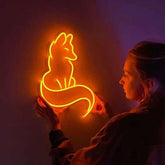 Person holding a neon sign of a fox against a dark background