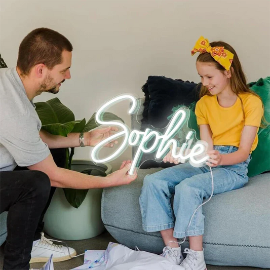 Man and young girl with a 'Sophie' text neon sign on a couch