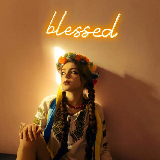 Woman in traditional attire with floral headpiece and 'blessed' neon sign