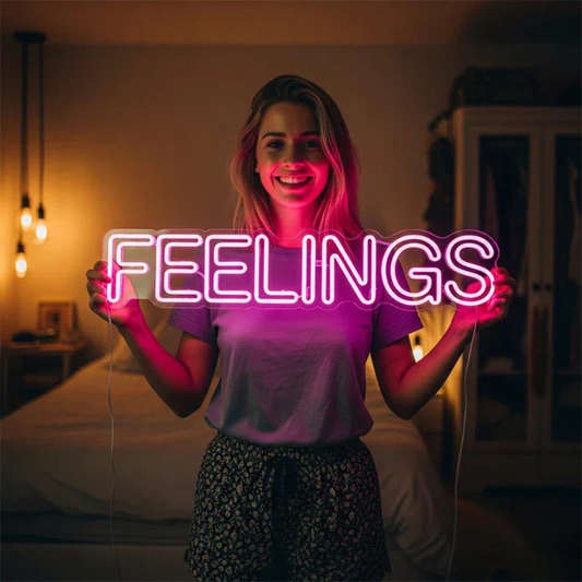 Person holding a neon sign with the word 'FEELINGS' in a dimly lit room.