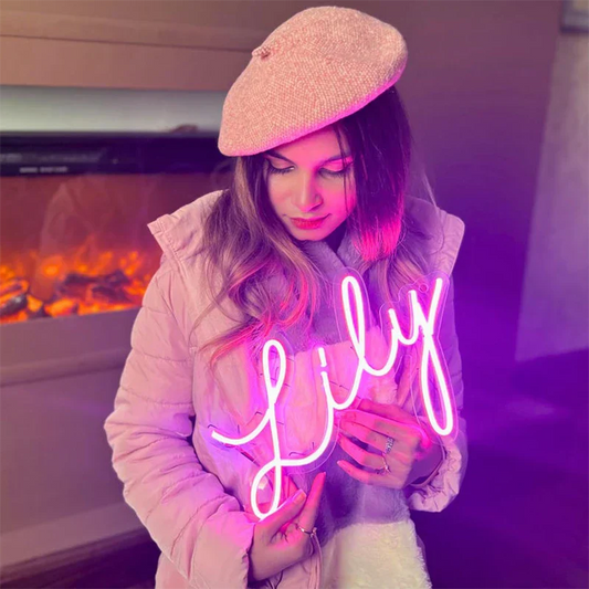 Person holding a neon sign with 'Lily' in front of a fireplace