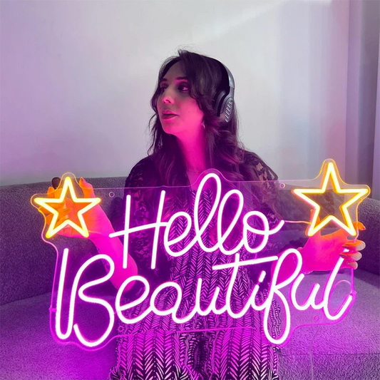 Person sitting on a couch with 'Hello Beautiful' neon sign in front