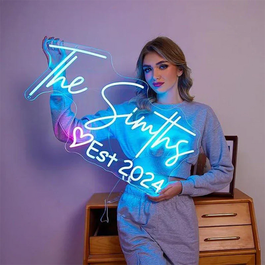 Person holding a neon sign with 'The Smiths Est 2024' on a purple background