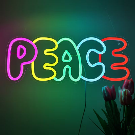 Neon sign spelling 'PEACE' with colorful letters on a dark background, accompanied by flowers.