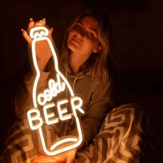 Neon sign shaped like a beer bottle with 'cold BEER' text, glowing in a dark setting.