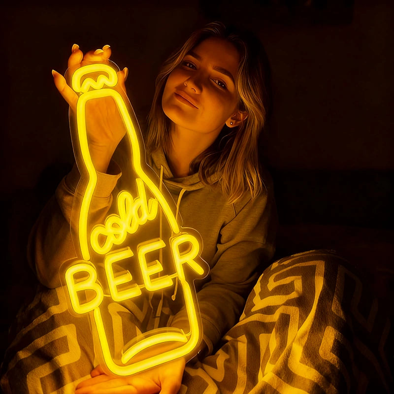 Person holding a lemon yellow neon sign shaped like a beer bottle with 'Cold Beer' text.