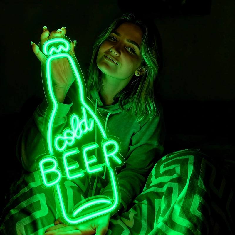 Person holding a neon green sign shaped like a beer bottle with the word 'cold BEER' inside.inside.