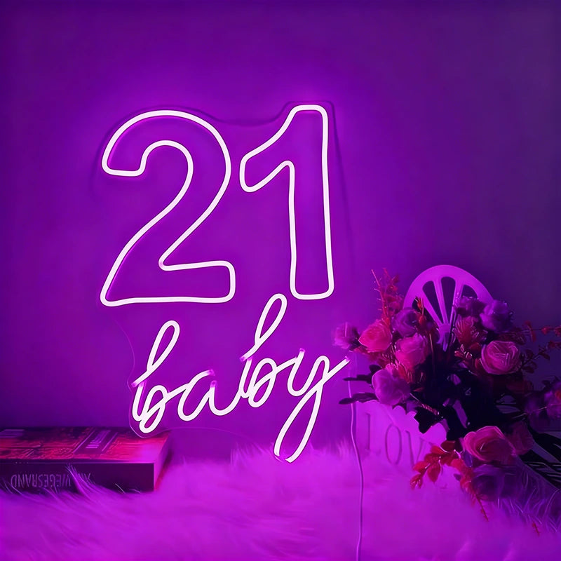 Neon sign with '21 baby' on a purple background with flowers and books.