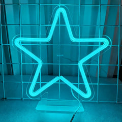Neon star-shaped light on a stand against a striped curtain background