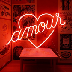 Neon sign with the word 'amour' in a heart shape on a red background