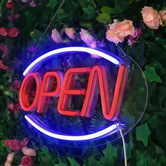 Neon 'OPEN' sign surrounded by flowers