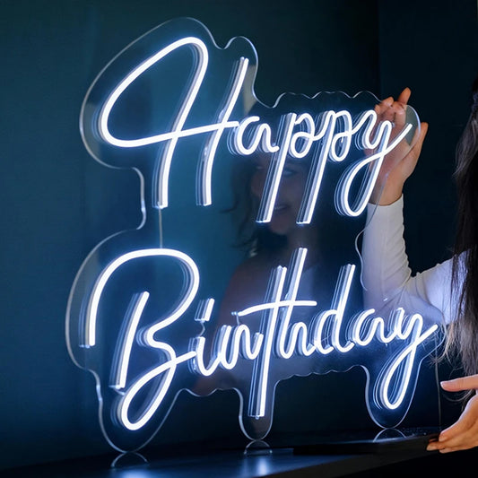 Neon sign with 'Happy Birthday' text held by a person against a dark background