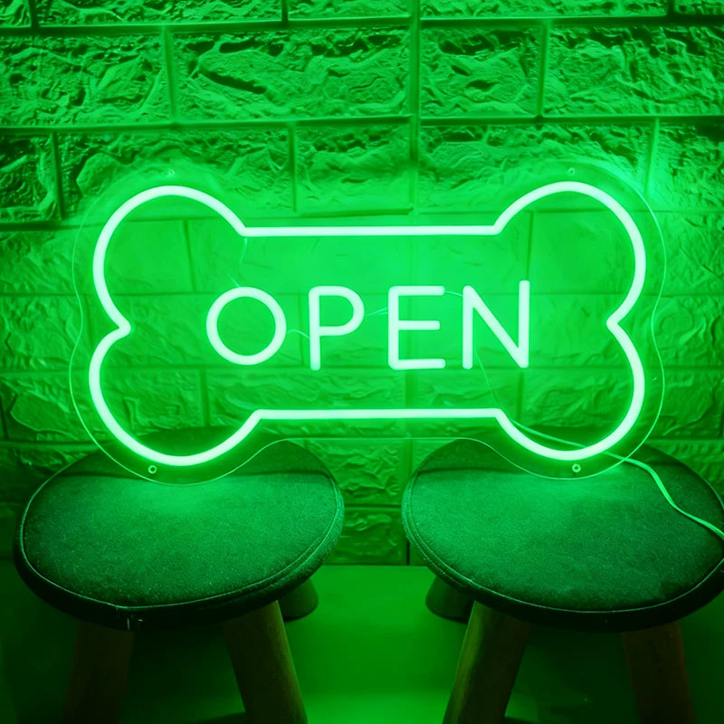 Green neon sign shaped like a bone with 'OPEN' text on a textured wall background.