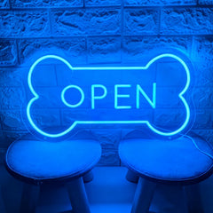 Blue neon sign shaped like a bone with 'OPEN' text on a textured wall background.