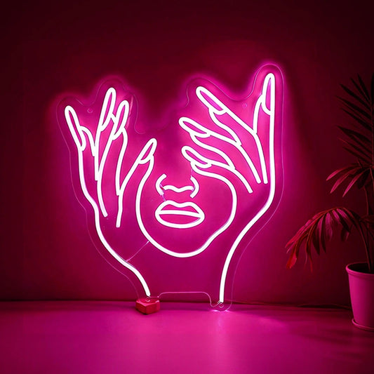 Neon hot pink light of hands holding a face on a dark background.