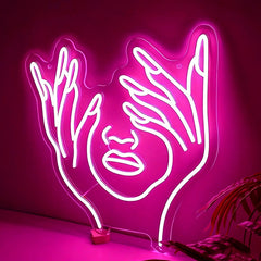 Neon hot pink light sculpture of hands holding a face on a dark background
