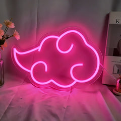 Pink neon cloud-shaped sign on a white surface with a blurred background