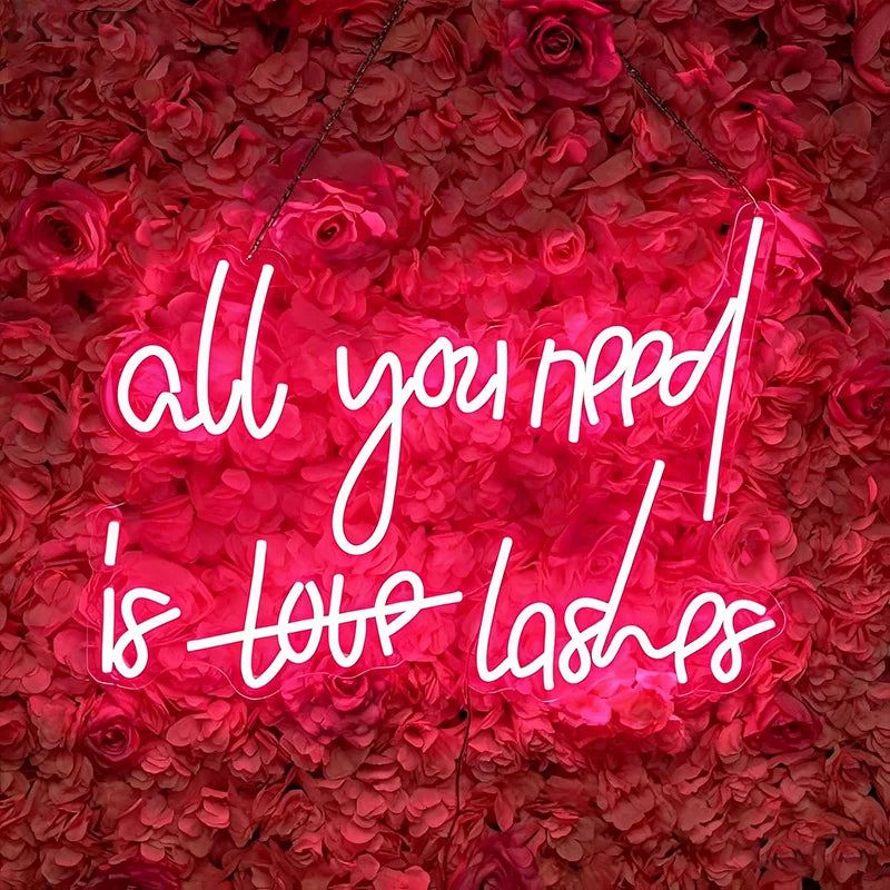 Neon sign with 'all you need is love lashes' on a red floral background
