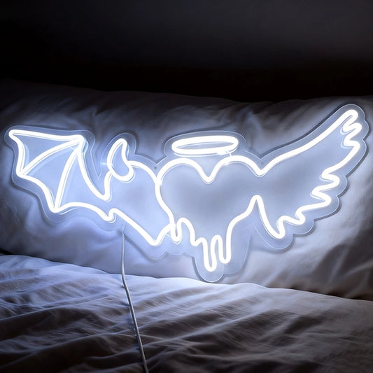 Neon light shaped like an angel with demon heart on a bed