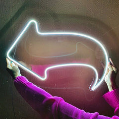 Neon light shaped like an arrow on a textured wall