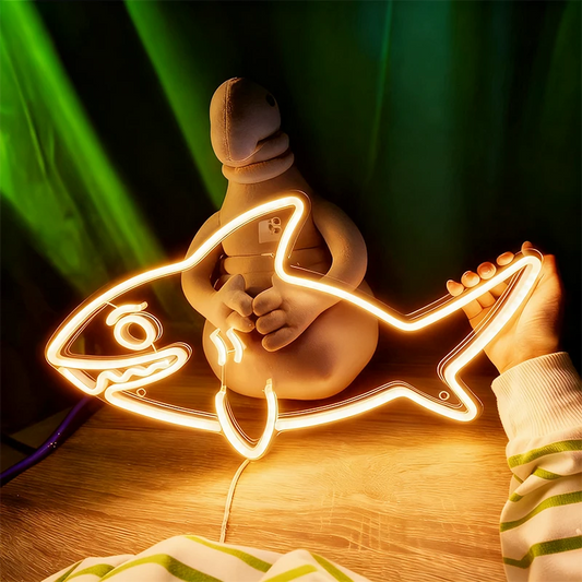 Warm white neon sign shaped like a fish with a person holding it, against a dark background.