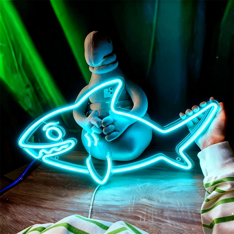 Ice blue neon sign shaped like a fish with a person holding it, against a dark background.