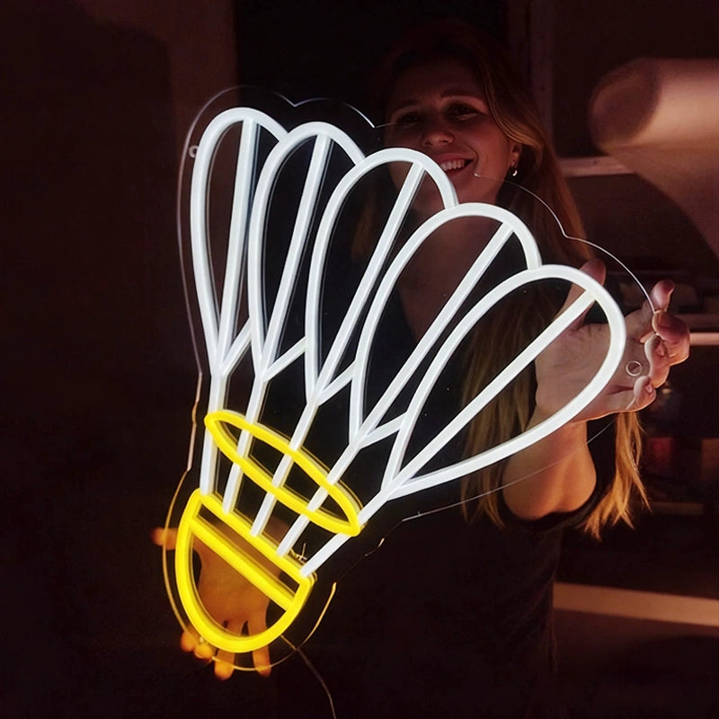 A smilling woman holding a neon shuttlecock light with lemon yellow and white color in a dark background
