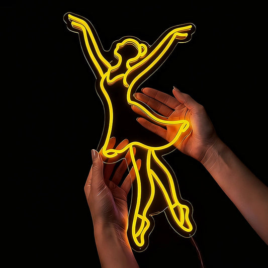 Person holding a lemon yellow ballet neon sign in a dark backgound