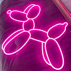 Neon hot pink balloon dog sign on a dark background