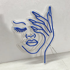 Blue neon outline of a beauty woman face and hand on a white wall