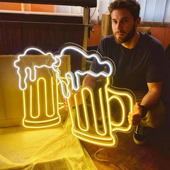 Man holding a beer mug neon sign in a casual setting.