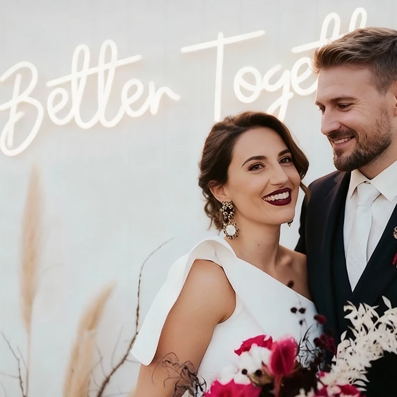 Couple posing together with 'Better Together' neon sign in the background