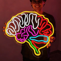 Person holding a neon light shaped like a brain with colorful illumination on a dark background