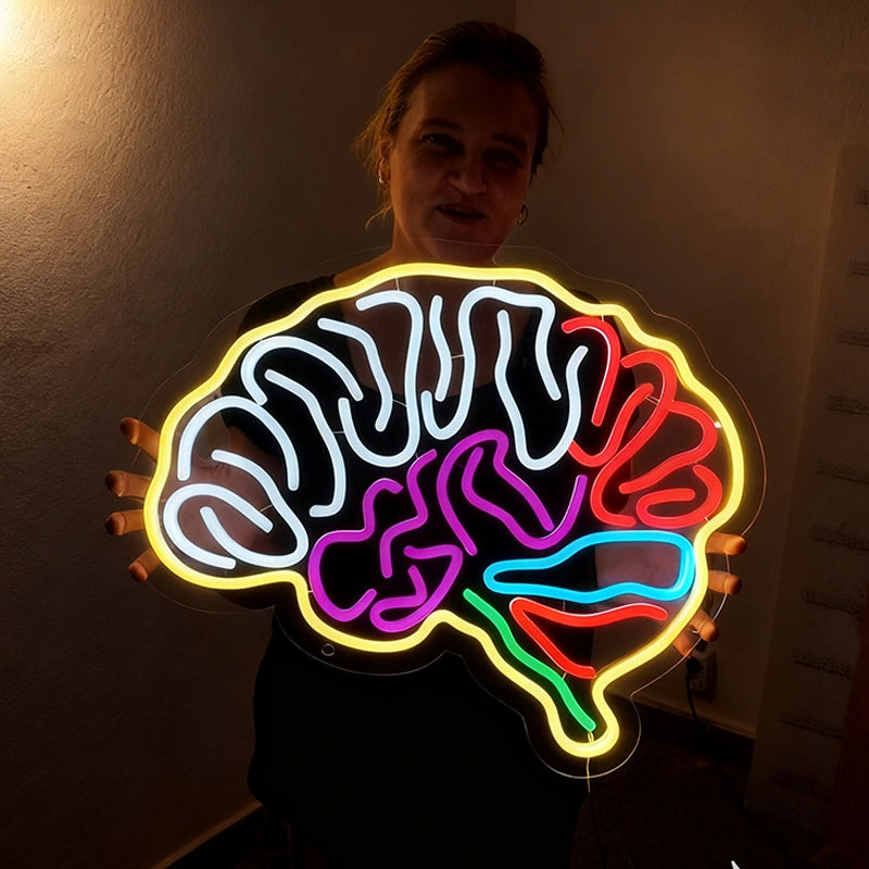Person holding a neon sign of a brain with colorful illumination.