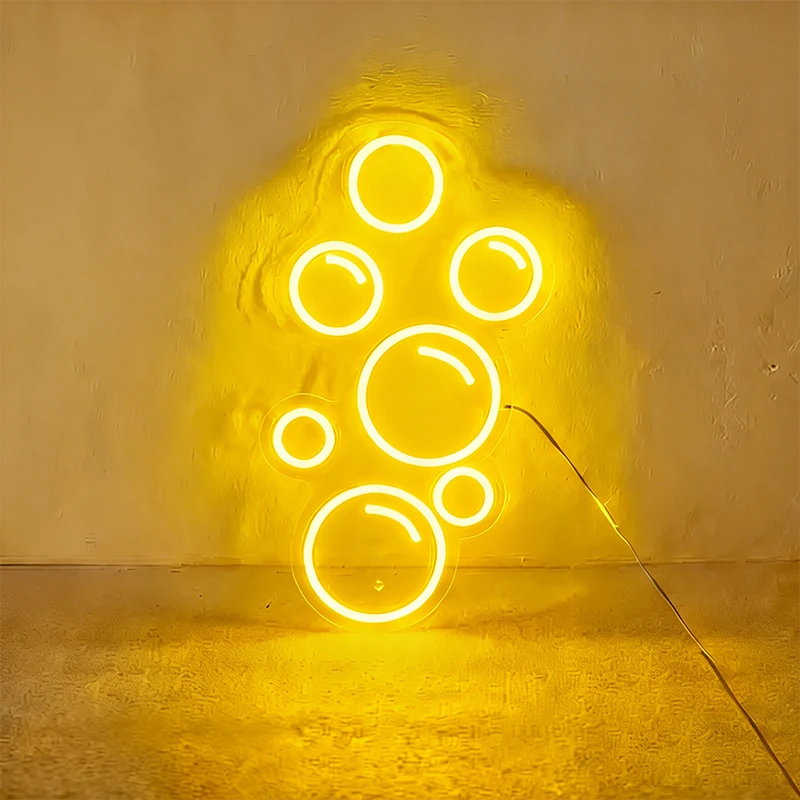 Lemon yellow neon light shaped like bubbles on a wall.