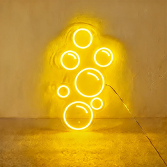 Lemon yellow neon light shaped like bubbles on a wall.