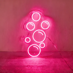 Hot pink neon light shaped like bubbles on a wall.